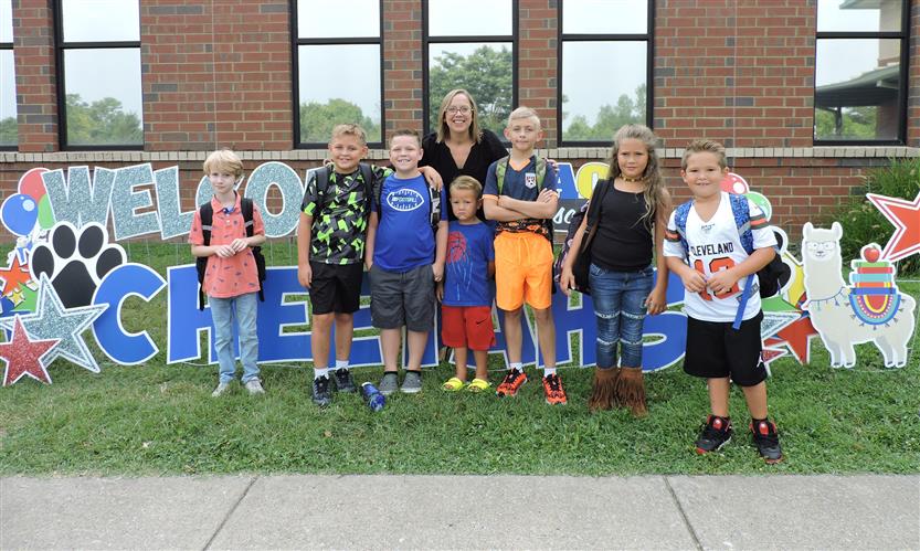 Students and parents stand in front of a Welcome Back sign
